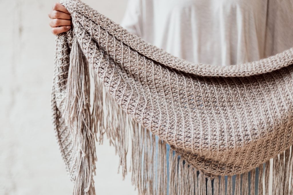 Make the Daydream Shawl, a beginner friendly Tunisian crochet boho triangle scarf. Pattern includes a helpful tutorial video! | FREE Tunisian Crochet Boho Fringe Wrap Pattern from TLYCBlog and JOANN. 