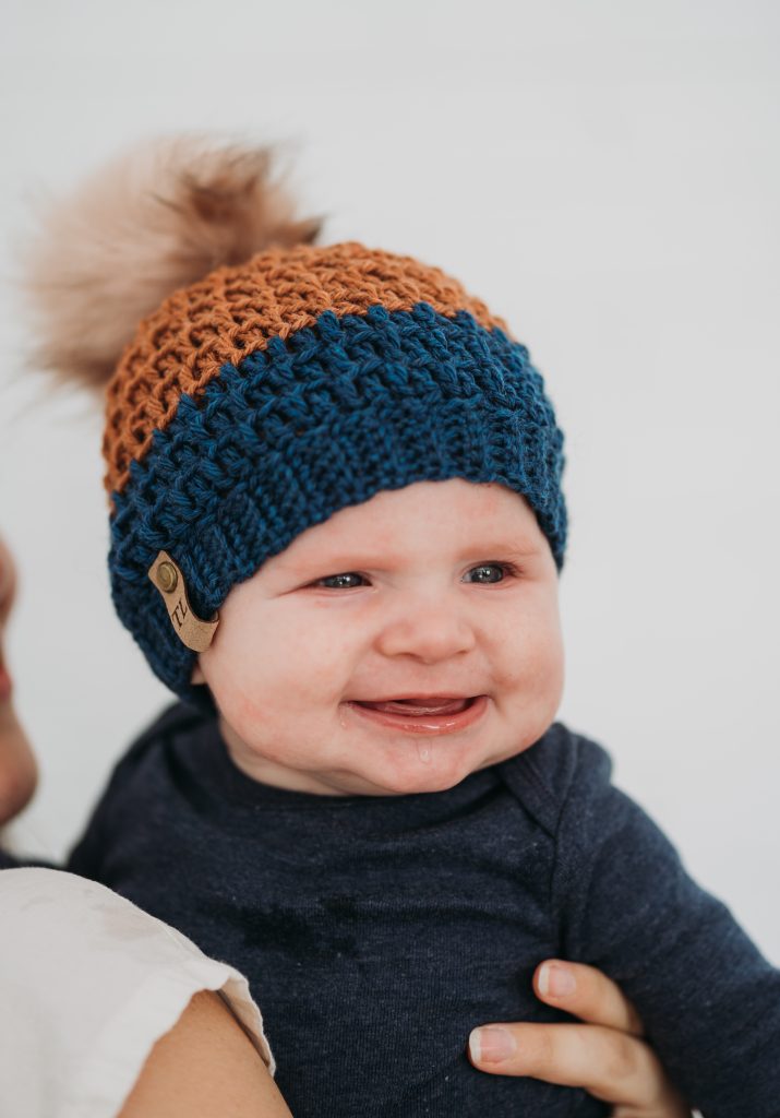 Mega Pom Beanie | Looking for a unique crochet slouchy hat that is perfect for the whole family? Try the Mega Pom Beanie, the ideal winter crochet hat pattern that includes sizes Newborn, 0-6 months, 6-12 months, 1-3 years, 3-10 years, and Teen/Adult. Babies, children, teens, and adults will love wearing this trendy hat, and you'll love making it. Beginner-friendly, it's one project you won't get enough of. Try the Mega Pom Beanie crochet hat pattern now. | TLYCBlog.com