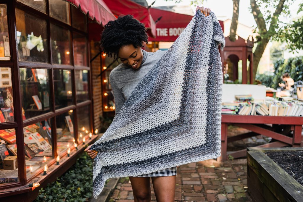 Learn to crochet this easy beginner crochet triangle scarf. The Omar Wrap features crochet v-stitches, ribbing, and color changing cake yarn.