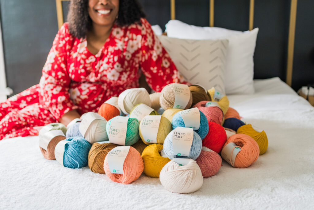 Hobbii Happy Place Yarn TL Yarn Crafts Yarn on Bed Woman Smiling at Yarn