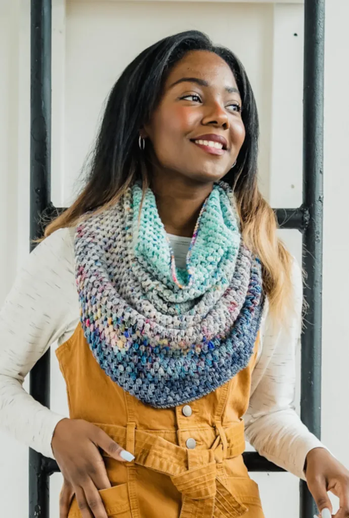 Model wearing the Juniper Cowl by TL Yarn Crafts, a deep, drapey crochet cowl made with soft, multicolored yarn advent minis blended into a textured gradient.