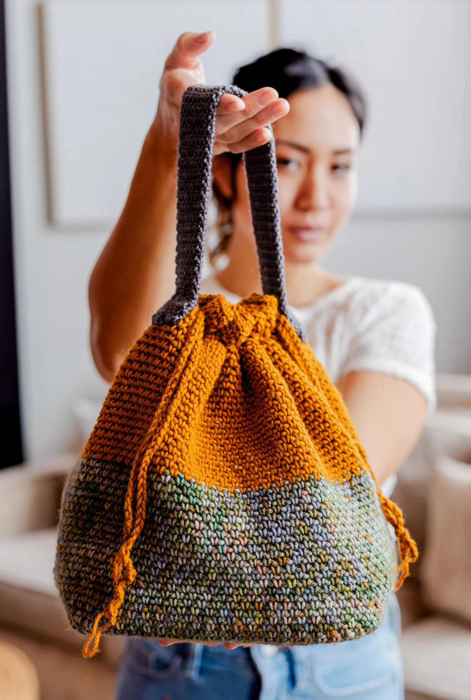 Crocheted Square One Project Bag made with DK-weight yarn, featuring a drawstring top and sturdy handles.