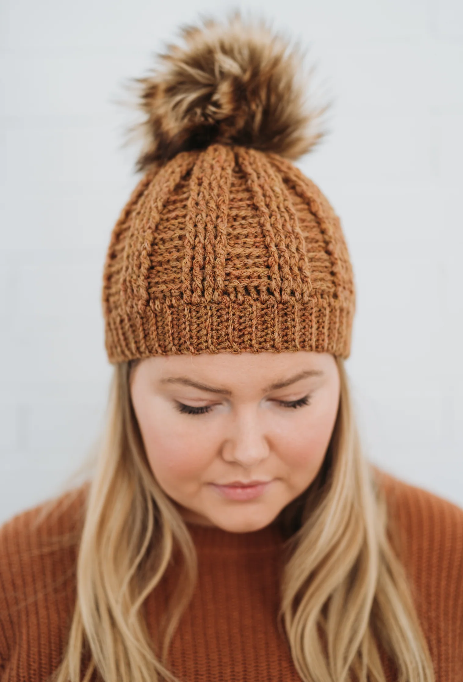 Model wearing the Barclay Beanie crochet pattern made with worsted weight yarn, featuring textured stitches and a pom-pom top.