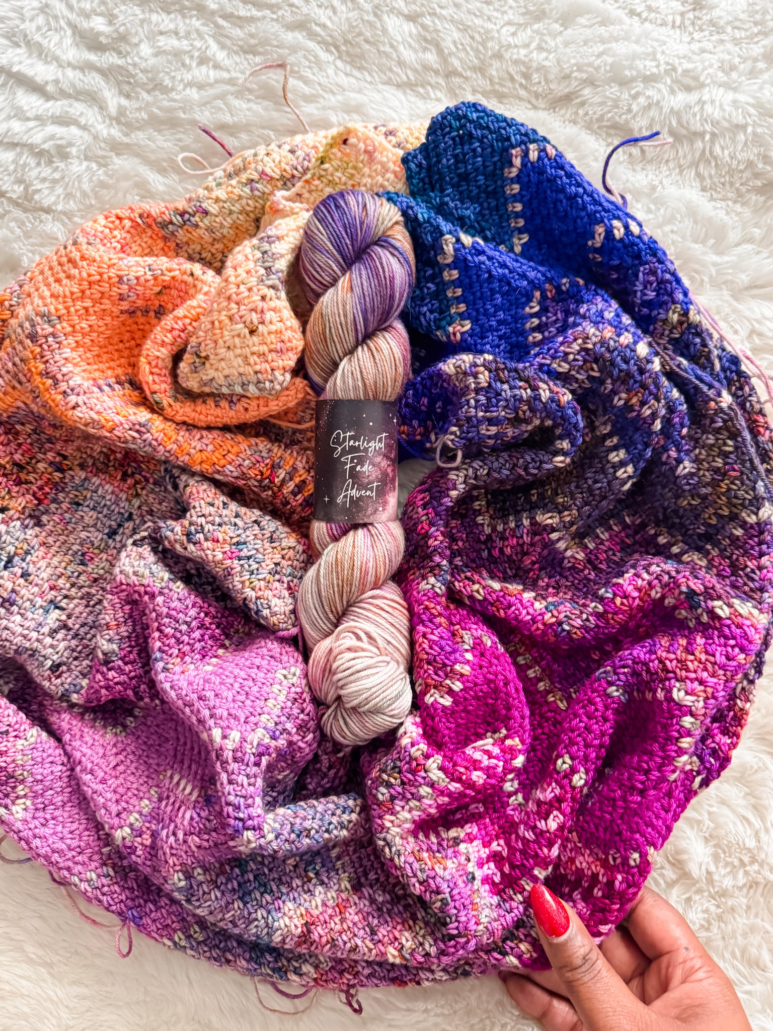 Astral Advent Wrap crochet chevron wrap showing a fade from warm pinks and purples to deep violet, made with mini skein advent yarn
