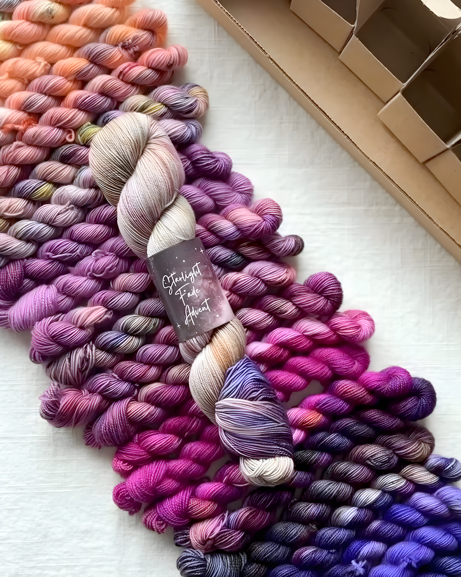 Hue Loco Starlight Fade Advent yarn showing a gradual fade from light peach and cream to rich purple and violet tones