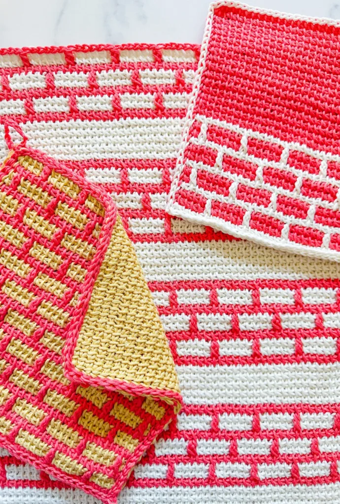 Handmade Tunisian crochet kitchen set featuring a washcloth, hand towel, and double-thick potholder with colorful textured stitch details.