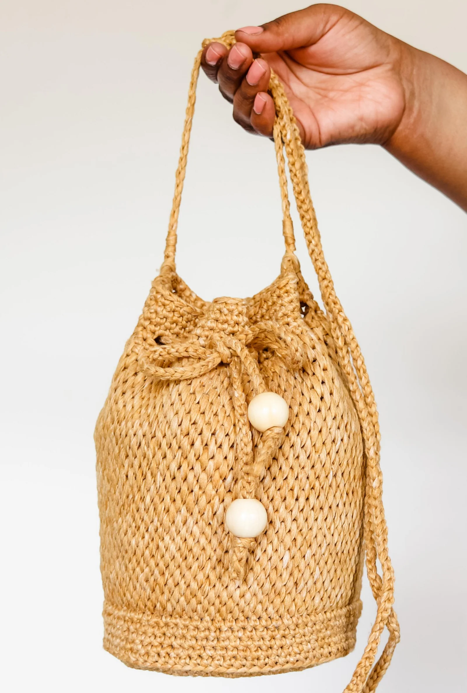 Harper Bucket Bag by TL Yarn Crafts, a textured crochet and Tunisian crochet drawstring bag with tassel ties in a warm neutral tone.