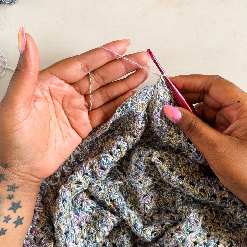 Crocheter holding the working yarn loosely across an open hand and index finger.