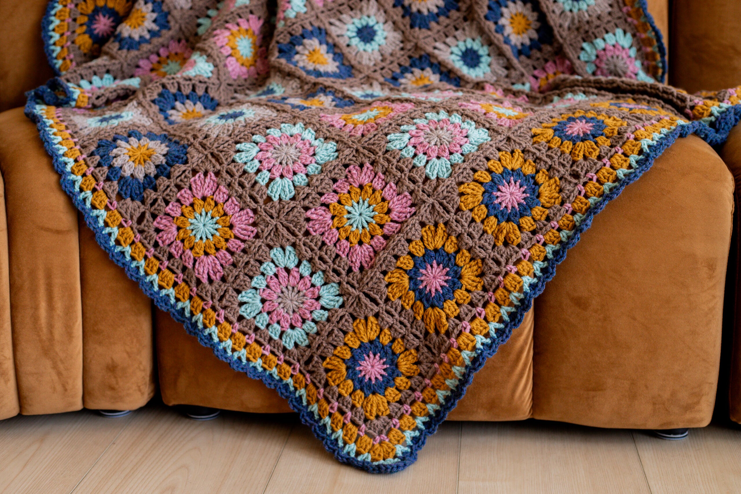 Color crochet granny square blanket on a couch - free crochet pattern + tutorial video available