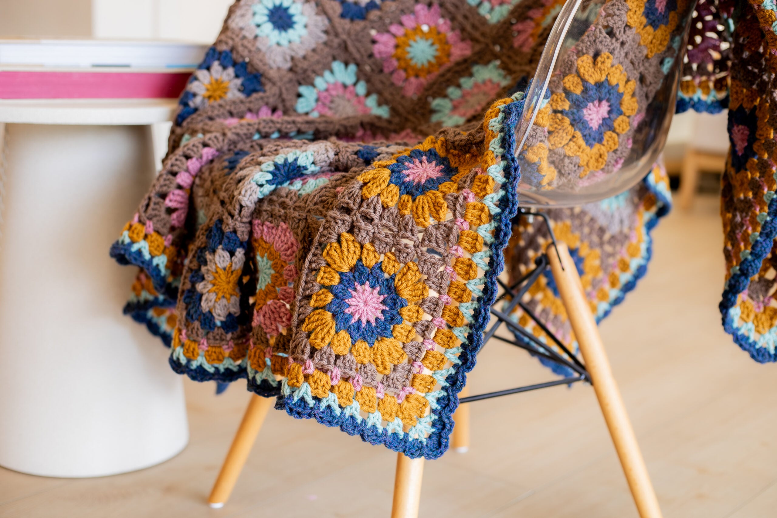Colorful crochet granny square blanket draped over a chair