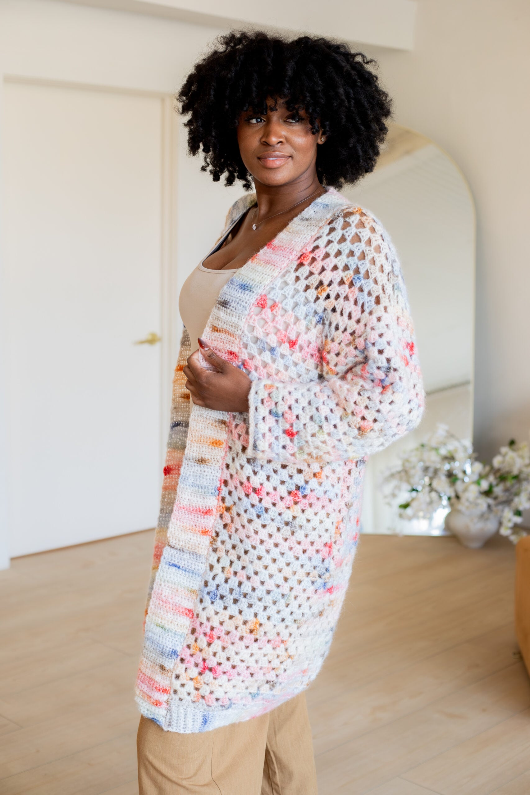 Woman wearing a pink and blue granny square cardigan - free crochet pattern