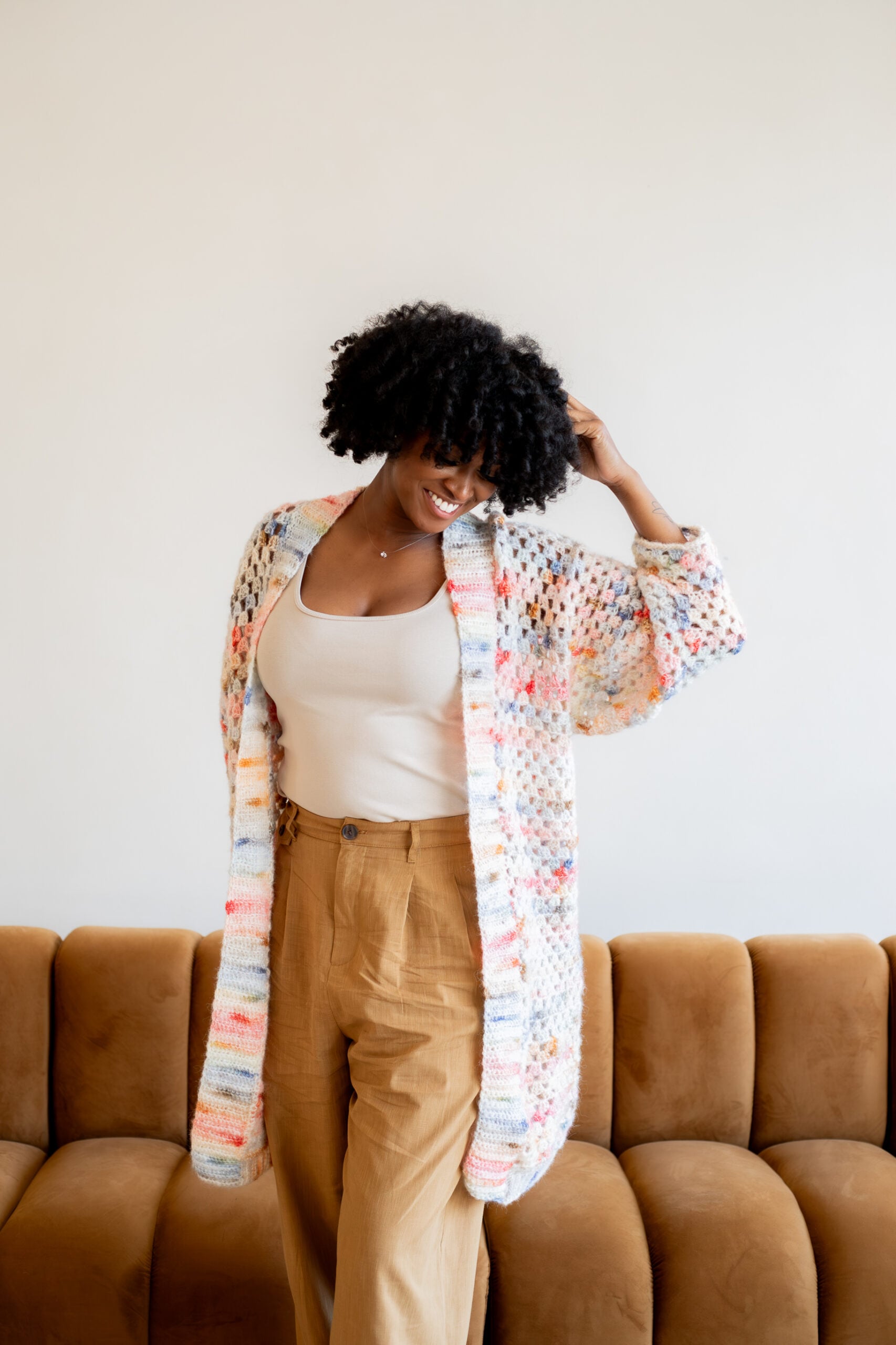Woman wearing a pink and blue granny square cardigan - free crochet pattern