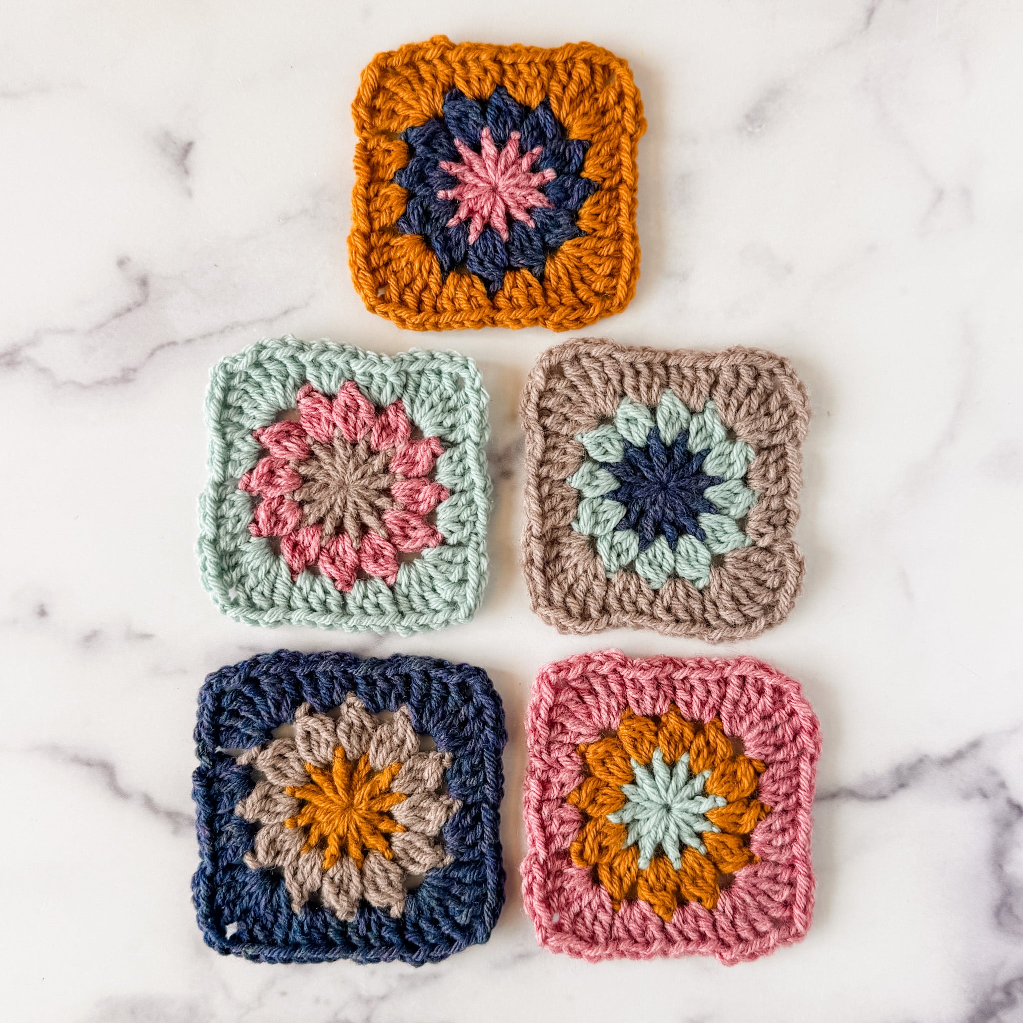 Five woodstock granny squares in different colorways lying flat